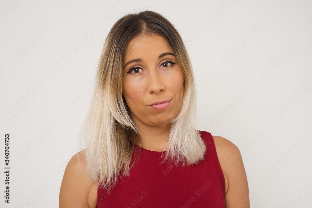 Waist up shot of joyful young woman looking to the camera, thinking or wondering about something. Both arms down, neutral facial expression. Waist up shot of joyful young woman looking to the camera, thinking or wondering about something. Both arms down, neutral facial expression.