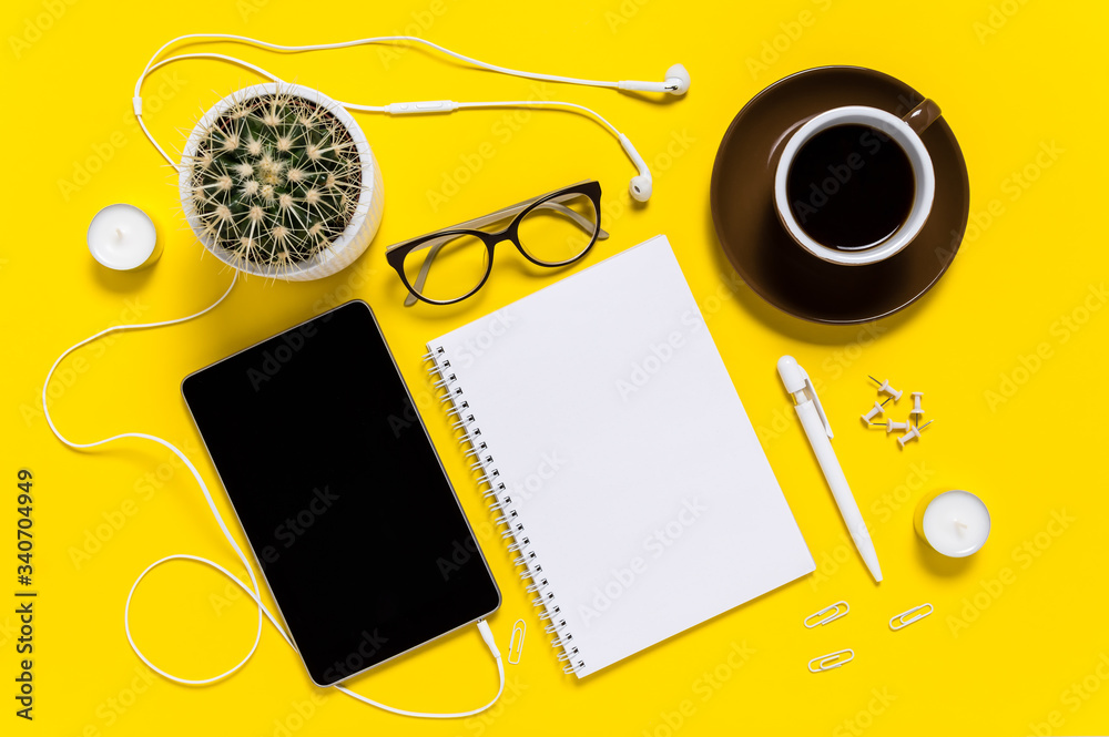 Flat lay of modern home office workspace with tablet, coffee cup, note pad, pen, eyeglasses and cactus on yellow background. Top view Flat lay of modern home office workspace with tablet, coffee cup, note pad, pen, eyeglasses and cactus on yellow background. Top view