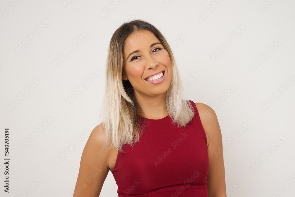 Beautiful smiling brunette female with broad smile, shows white teeth, wears casual t shirt, stands over gray studio wall rejoices having day off. Woman standing indoors. Beautiful smiling brunette female with broad smile, shows white teeth, wears casual t shirt, stands over gray studio wall rejoices having day off. Woman standing indoors.