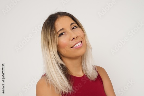 Shy girl smiling looking to the camera. Caucasian charming girl sanding against gray studio background feeling shy.