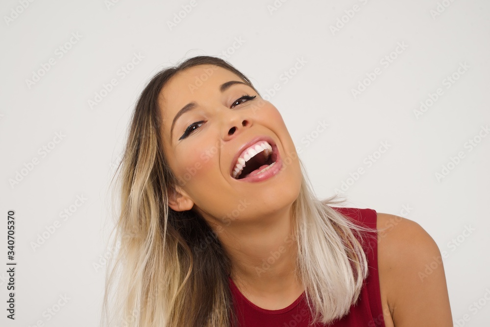 Joyful European woman having fun and laughs at good joke or sings wears casual clothes, standing against gray wall. Happy woman with long hair poses inddoors. Joyful European woman having fun and laughs at good joke or sings wears casual clothes, standing against gray wall. Happy woman with long hair poses inddoors.