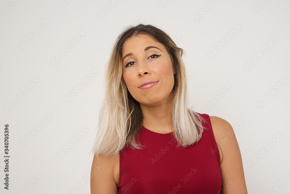 Close up studio shot of beautiful young mixed race woman model with curly dark hair looking at camera with charming cute smile while posing against white blank copy space wall for your content Close up studio shot of beautiful young mixed race woman model with curly dark hair looking at camera with charming cute smile while posing against white blank copy space wall for your content