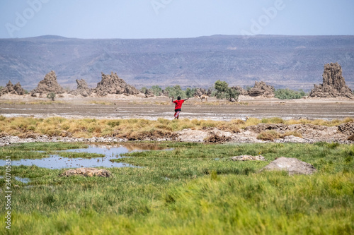 A nomadic child is walking around lake Abbe with a stick