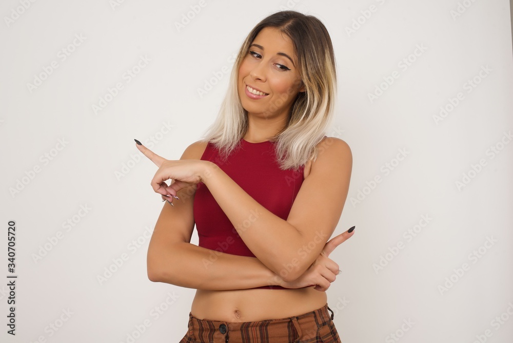 Pretty brunette woman posing on camera with tricky look and gesturing to side. Female designer presenting lovely product with index finger. Gesture concept. Pretty brunette woman posing on camera with tricky look and gesturing to side. Female designer presenting lovely product with index finger. Gesture concept.