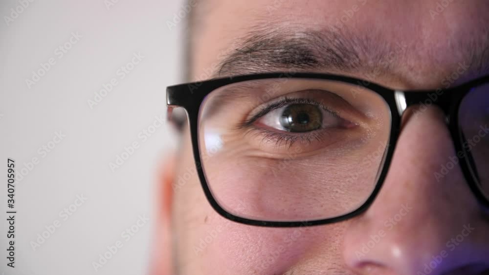 Close-up face of a male eyes with glasses works at the computer. Display reflection in glasses. Portrait of a young man programmer with glasses. Work in home. Quarantine Close-up face of a male eyes with glasses works at the computer. Display reflection in glasses. Portrait of a young man programmer with glasses. Work in home. Quarantine