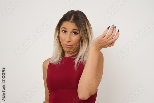 What the hell are you talking about, nonsense. Studio shot of frustrated female with blonde hair gesturing with raised palm, frowning, being displeased and confused with dumb question over gray wall.