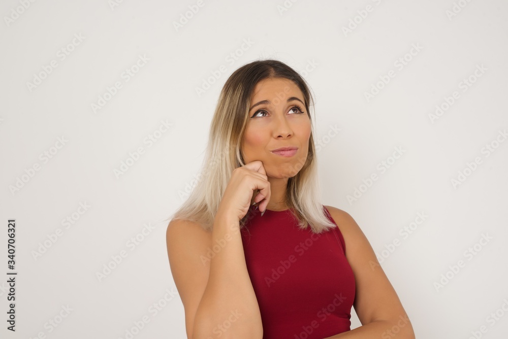 Face expressions and emotions. Thoughtful young pretty girl in blue sweater holding hand under her head, having doubtful look. Face expressions and emotions. Thoughtful young pretty girl in blue sweater holding hand under her head, having doubtful look.