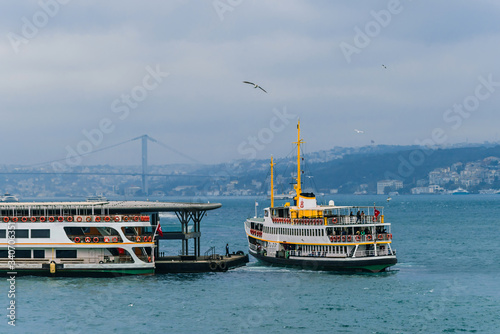 Tourist ferry ride along the Golden horn Bay in Istanbul. Tourist ferries in the Golden horn Bay on the background of the bridge. Cloudy weather © Konstantin