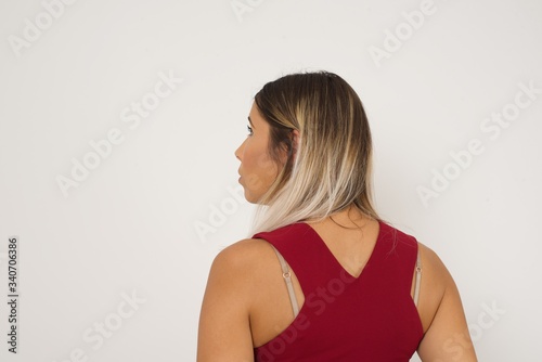 The back side view of a girl with long straight wavy and shiny hair standing against gray wall. Studio Shoot.ï¿½