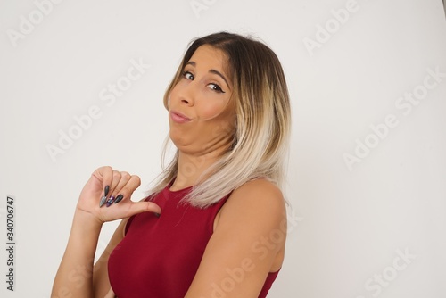 Closeup of cheerful beautiful European young woman looks joyful, satisfied and confident, points at herself with thumb, isolated over studio background.