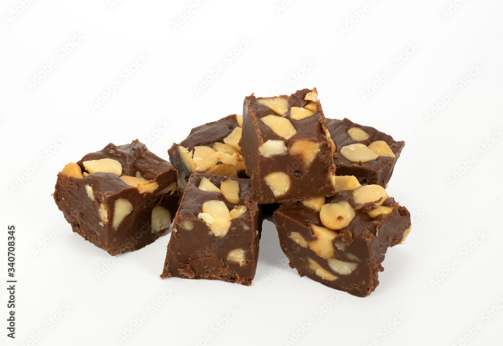 Chunks of homemade chocolate macadamia nut fudge stacked against a white background. Chunks of homemade chocolate macadamia nut fudge stacked against a white background.