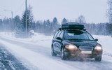 Car with roof rack and winter snowy road in Rovaniemi reflex