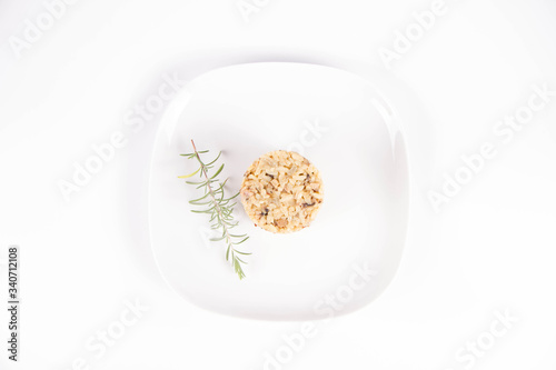 Risotto with button mushroom and bacon decorated with rosemary twig on a plate on a white background photo