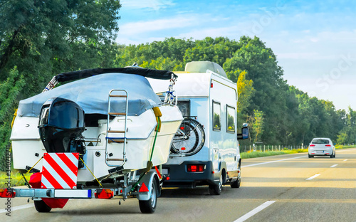 Caravan and trailer for motor boats on road in Switzerland reflex