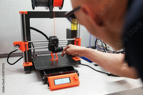 Man checking 3d printer with display, process of making things on 3d printer in laboratory