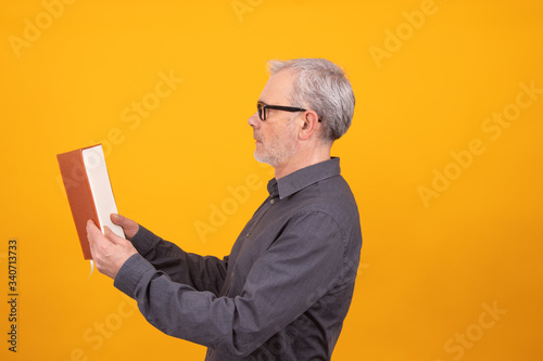 adult or senior man with book isolated on color background