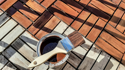 Repair concept. the brush lies on a jar with a protective varnish for wood. Half of the terrace is covered and the other is not. top view