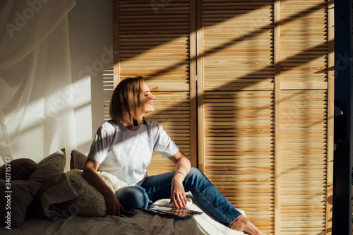 girl at home on a sunny day in a white t-shirt.wooden background blinds.  sun day