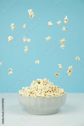 Dreamy image of popcorn falling from the sky over a bowl full of popcorn.