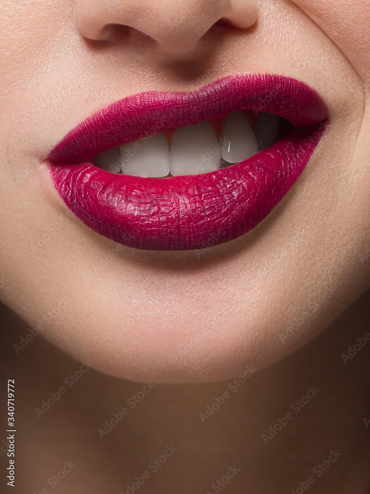 Obraz premium Close-up of sexy female lips with tongue. Clean skin and a clear lip contour are outlined with a fashionable marsala lipstick. White teeth and the beauty of smile for stamotologii, spa or cosmetology
