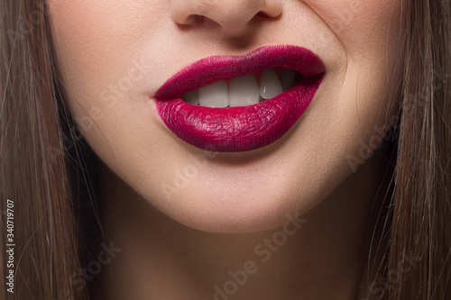 Close-up of sexy female lips with tongue. Clean skin and a clear lip contour are outlined with a fashionable marsala lipstick. White teeth and the beauty of smile for stamotologii  spa or cosmetology