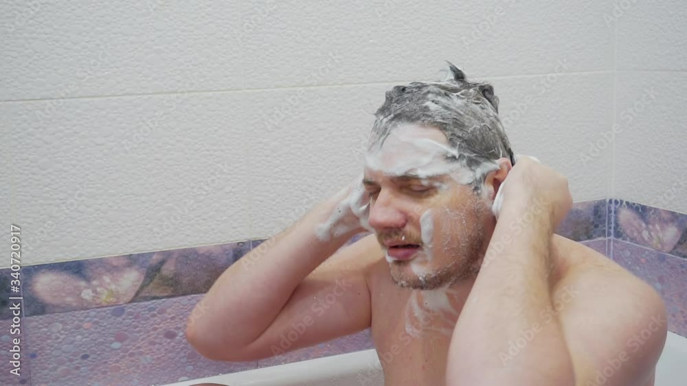 modern young man washing his head while sitting in a bath. modern young man washing his head while sitting in a bath.