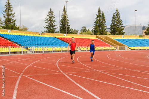 Wallpaper Mural funny children run a race around the sports stadium. children at the event. empty sports stands. Torontodigital.ca