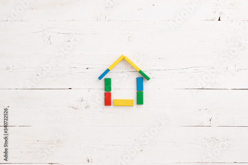 Colored wooden cubes assembled in the shape of a house on a white wooden background. Early development for children. Home, family and education concept.