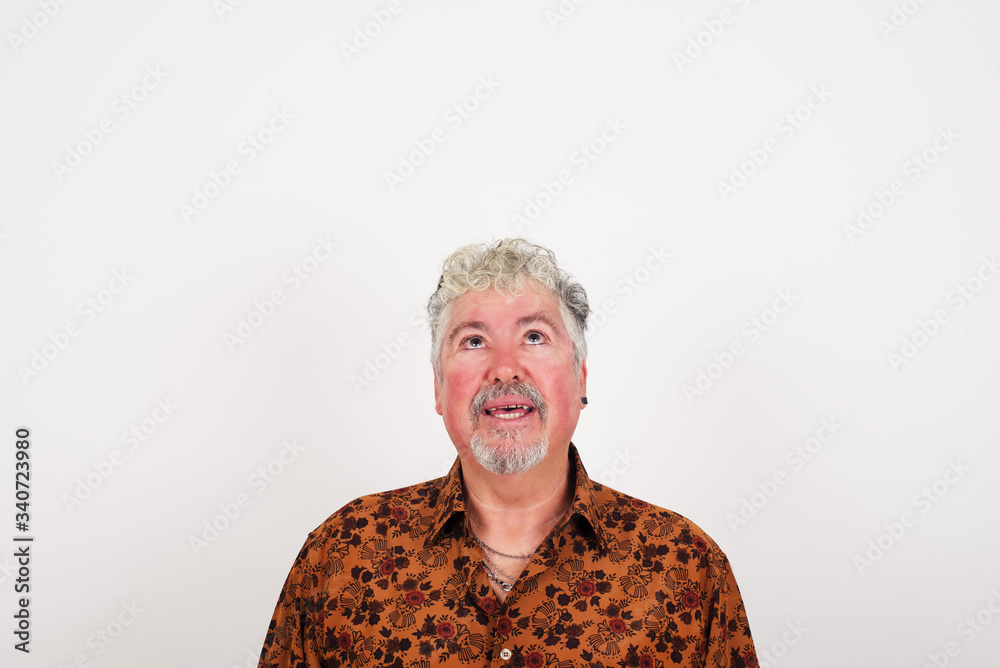 Portrait of mysterious charming blond male looking up with enigmatic smile. Handsome smiling guy looking up standing against gray wall. Portrait of mysterious charming blond male looking up with enigmatic smile. Handsome smiling guy looking up standing against gray wall.