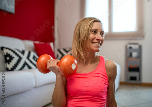 Portrait of a woman with weights does gymnastics exercises in the house.