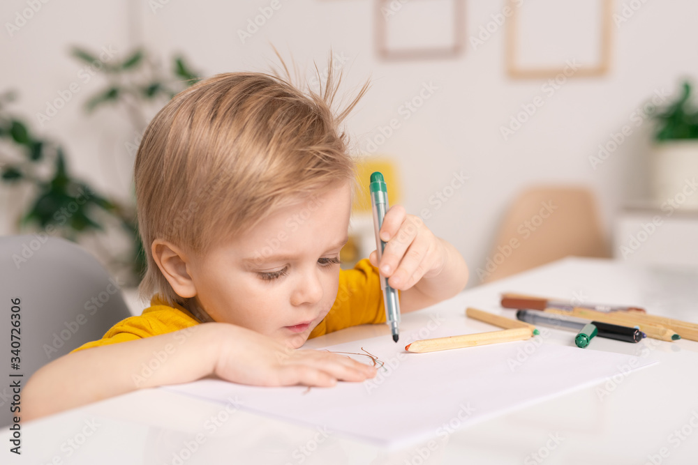 Cute little boy with green crayon or highlighter over paper drawing picture Cute little boy with green crayon or highlighter over paper drawing picture