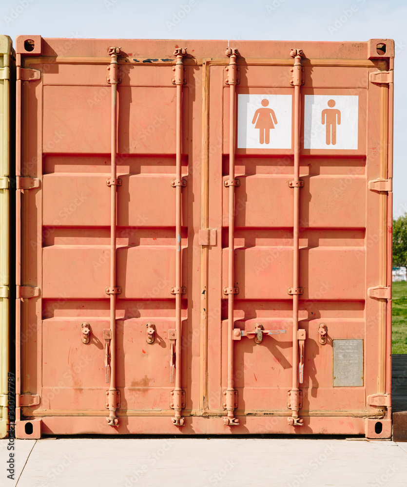 White screen printing of a public toilet symbol on an orange shipping container White screen printing of a public toilet symbol on an orange shipping container