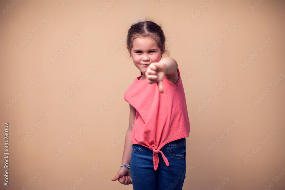 A portrait of kid girl showing thumb down sign. Children and emotions concept A portrait of kid girl showing thumb down sign. Children and emotions concept