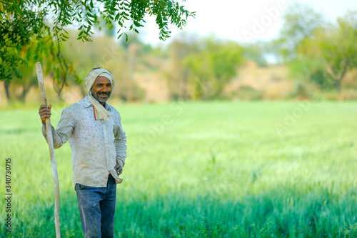 Young Indian farmer standing at wheat field © PRASANNAPIX