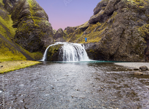View from flying drone of Stjornarfoss waterfall. with person Impressive summer sunrise in Iceland, Europe. Beauty of nature concept background. Travel to Iceland..