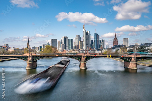 Frankfurt, Germany - March 31, 2020: frankfurt skyline view with a cargo ship passing underneath ignas bubis bridge photo