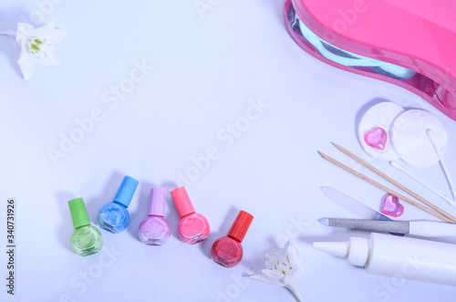 Multi-colored nail polishes on a white background with a lamp for drying manicure and accessories. Beauty concept. Theme of manicure.