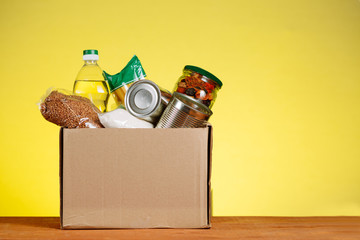 Food Donation concept. Donation Box With food For Donation On Yellow Backround. Assistance To The Elderly In The Context of The Coronavirus Pandemic