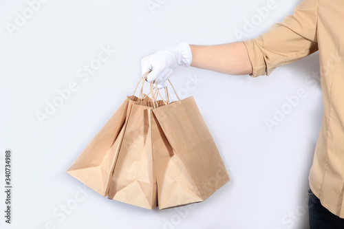 A man in a uniform and white gloves is holding a paper shopping bag. Unrecognizable photo. The concept of service delivery. Advertising space. Copy of the space.