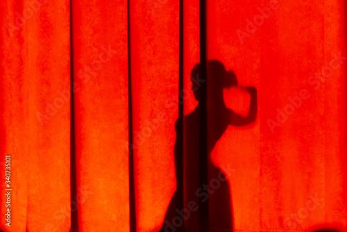 Female silhouette on the curtain. The shadow of a girl dancing on colored canvases.