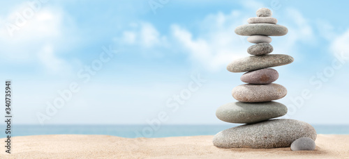 Pyramid of sea pebbles on a sunny sand beach