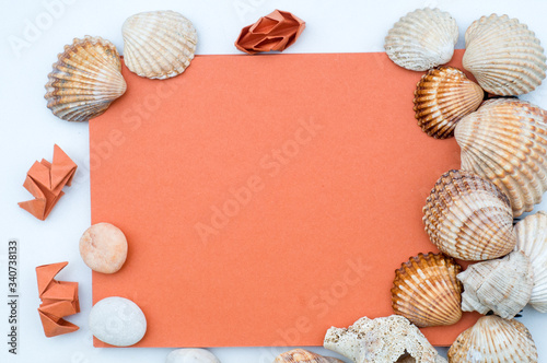 Seashells, origami and orange notepad on white background. Colorful flat lay design. Decorations. Colorful background. Objects on wooden table. Copy space concept 