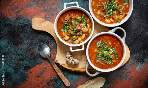 Fotografía Bean soup with meat and vegetables served on a rustic board with garlic