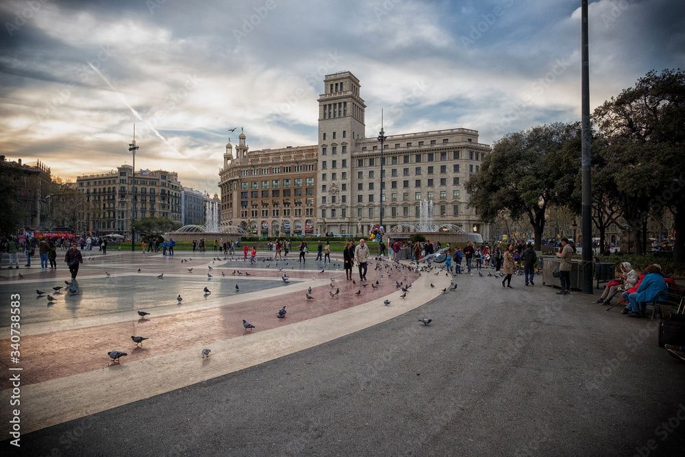 Tourists feed the pigeons on the Square of Catalonia (Placa de Catalunya) in Barcelona. Plaza de Catalunya is one of the main attractions of the Catalonia capital.