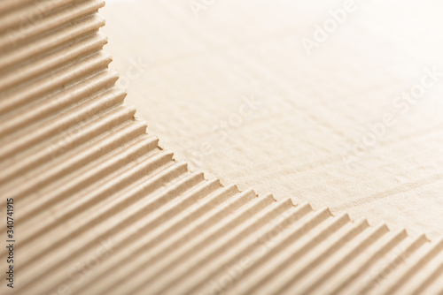 Carton or cardboard packing material. Texture of corrugated paper sheets made from cellulose. Supplies for creating boxes and packaging. Pasteboard background. Natural brown cardboard surface.