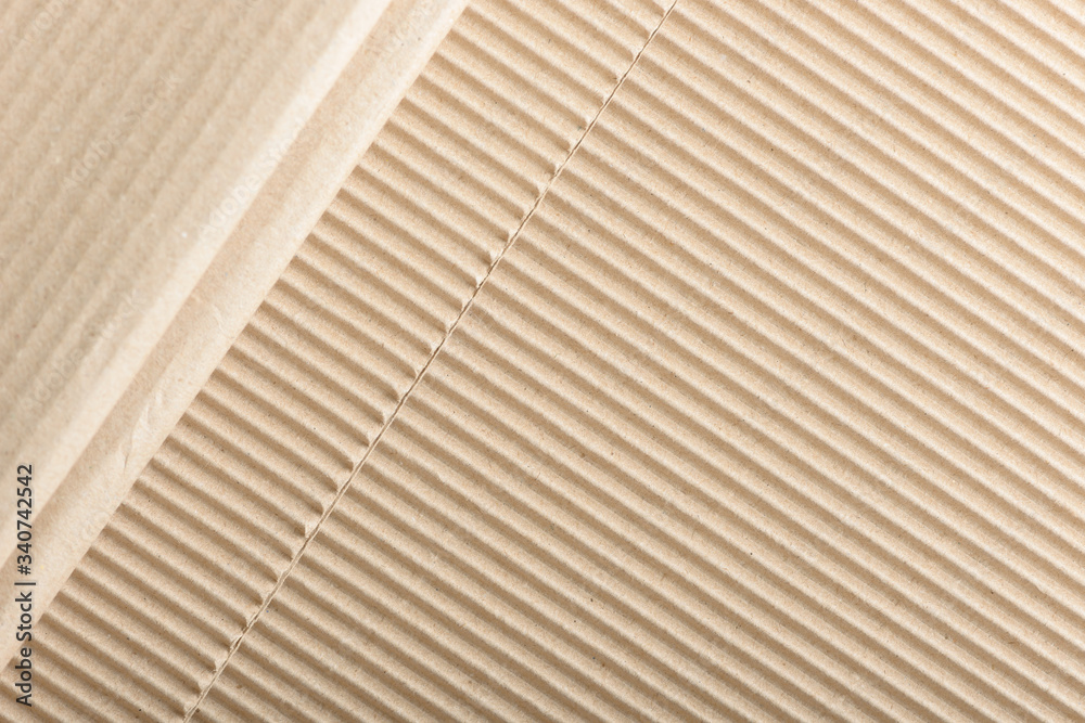 Fototapeta premium Carton or cardboard packing material. Texture of corrugated paper sheets made from cellulose. Supplies for creating boxes and packaging. Pasteboard background. Natural brown cardboard surface.