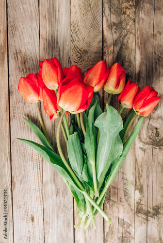 Real spring red tulips on a rustic wooden background. Spring flowers for Mother's Day. Top view.