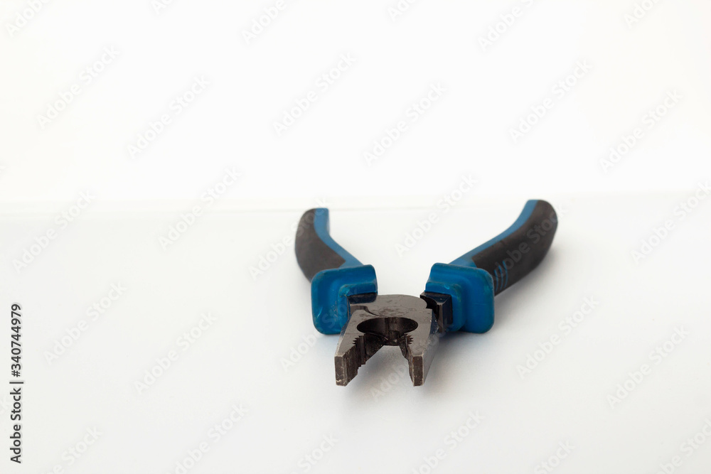 the pliers are on a bright white table. Blue repair tool the pliers are on a bright white table. Blue repair tool