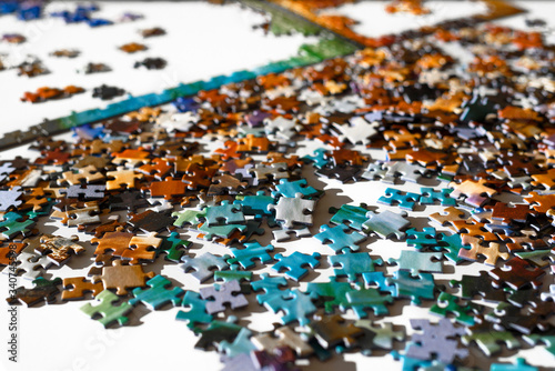 Scattered multicolored jigsaw puzzle pieces. Lying on white table in sun light. Concept of putting together elements and solving problems. photo