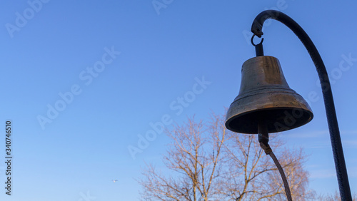 Close-up view of the old skool bronze fire bell on the classic blue sky background. Alarm fire concept. © kalyanby